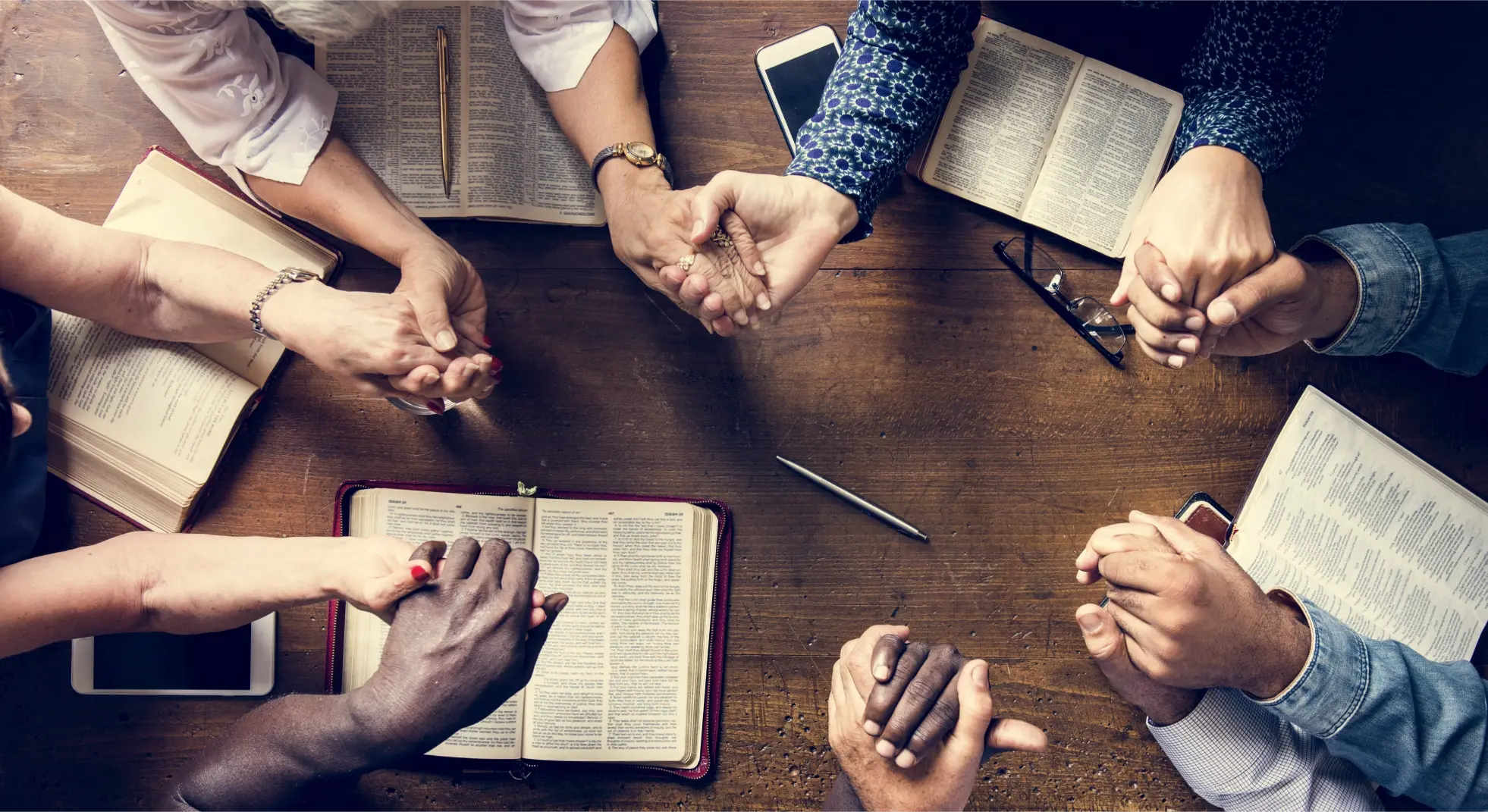 People holding hands praying around a table