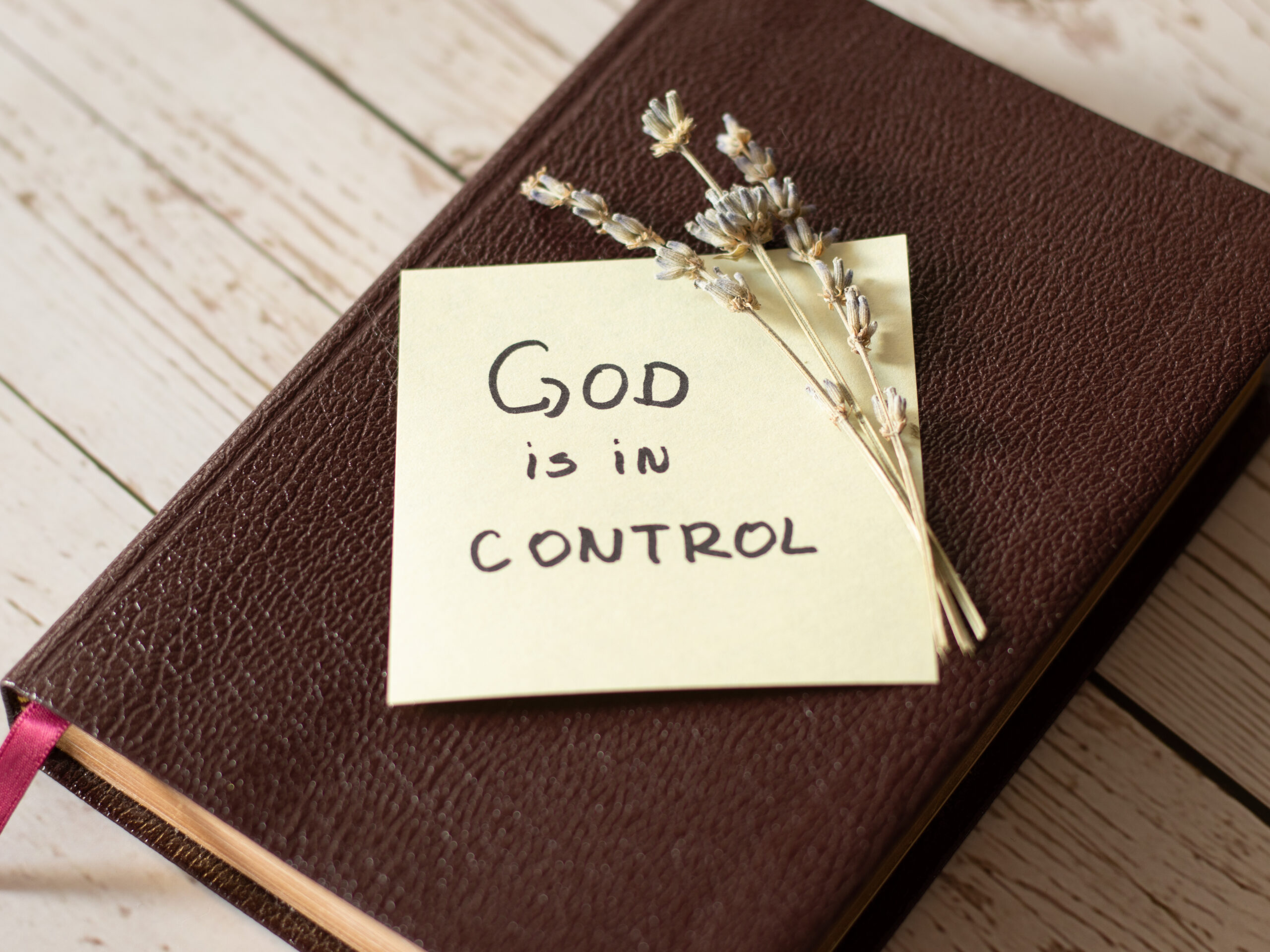 God is in control. Handwritten note on a closed Holy Bible.
